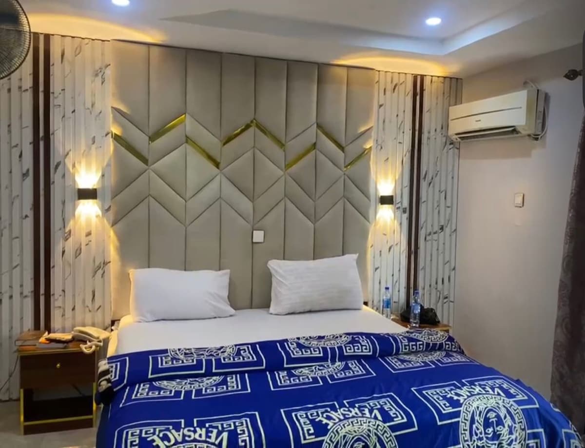 Super Deluxe room with chevron upholstered headboard and wall sconces